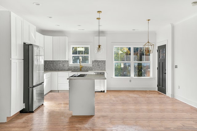 kitchen featuring stainless steel appliances, sink, white cabinets, a kitchen island, and hanging light fixtures