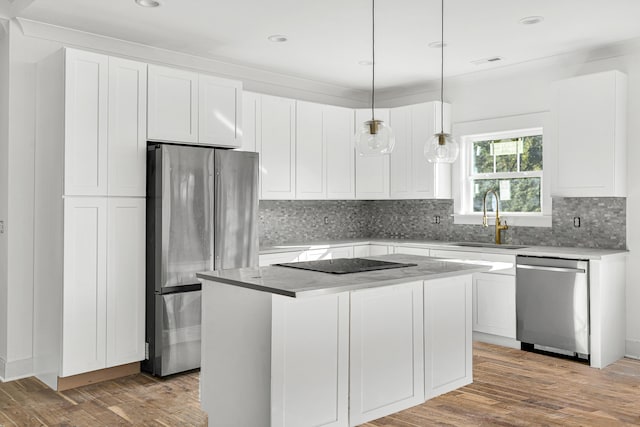 kitchen with a center island, sink, appliances with stainless steel finishes, decorative light fixtures, and white cabinetry