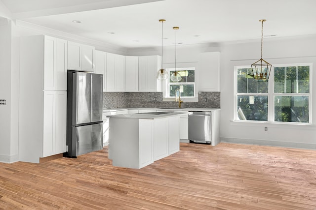 kitchen with white cabinetry, a center island, light hardwood / wood-style flooring, pendant lighting, and appliances with stainless steel finishes