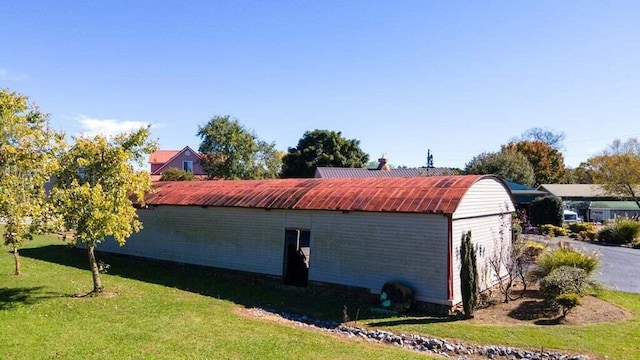 view of side of home featuring an outbuilding and a yard