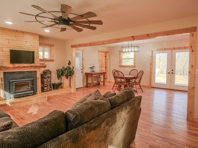 living room featuring ceiling fan, a large fireplace, light wood-type flooring, and french doors