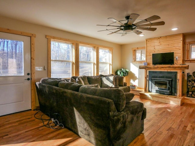 living room with hardwood / wood-style floors, ceiling fan, and a large fireplace