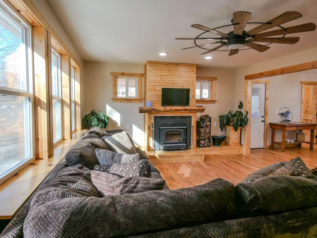 living room with a wood stove, light hardwood / wood-style flooring, and ceiling fan