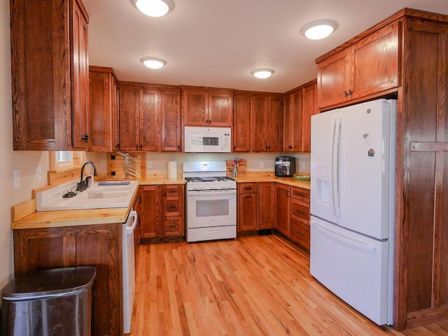 kitchen with sink, white appliances, and light hardwood / wood-style flooring