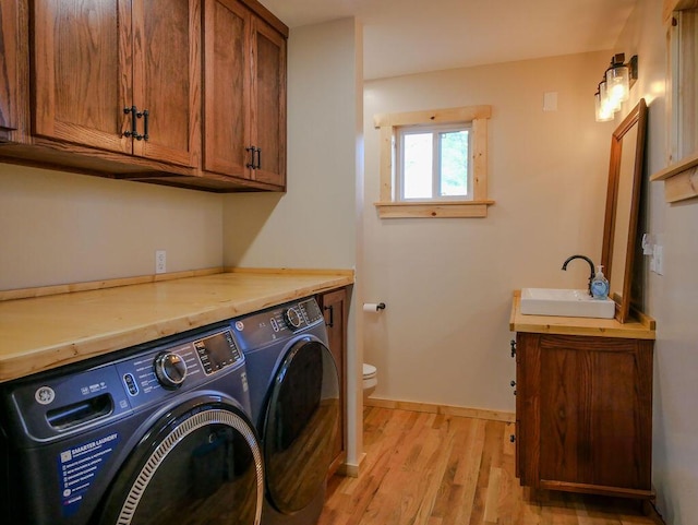 laundry room featuring washer and clothes dryer, sink, and light hardwood / wood-style floors