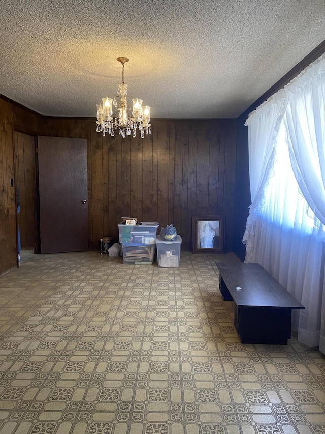 dining room with a textured ceiling, an inviting chandelier, and wood walls