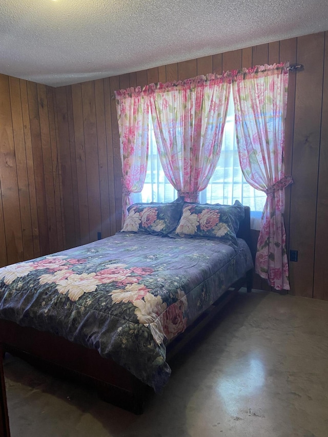 bedroom with a textured ceiling and wood walls