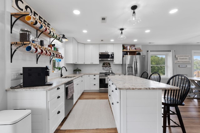 kitchen with stainless steel appliances, decorative light fixtures, sink, and white cabinets