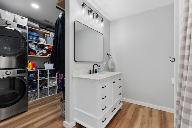 bathroom with vanity, stacked washer / drying machine, and hardwood / wood-style floors