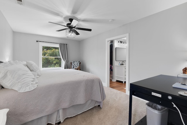 carpeted bedroom with ensuite bathroom and ceiling fan