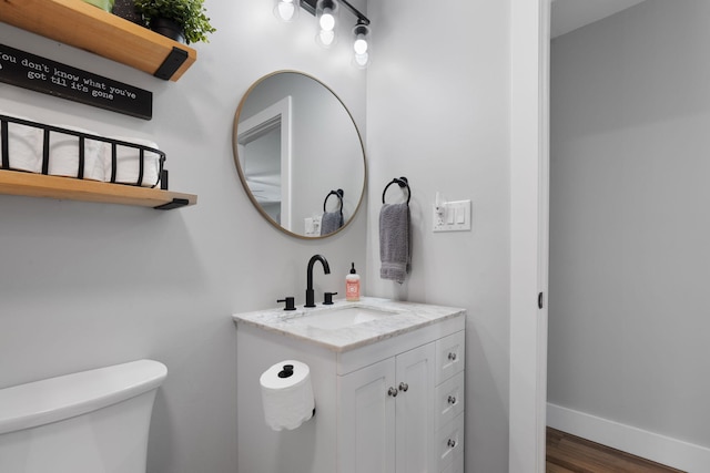 bathroom with vanity, toilet, and hardwood / wood-style floors