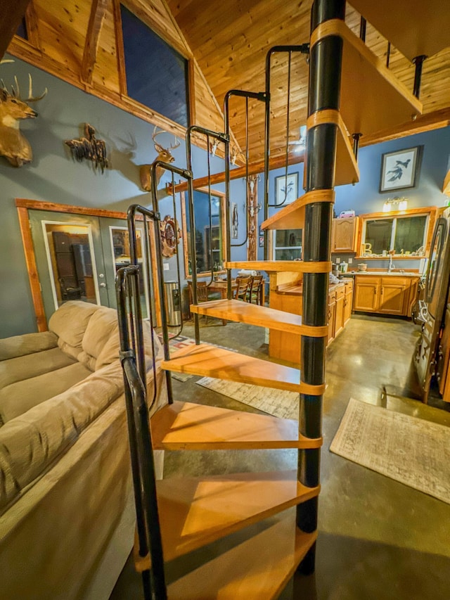 stairs with wooden ceiling, sink, high vaulted ceiling, and concrete flooring