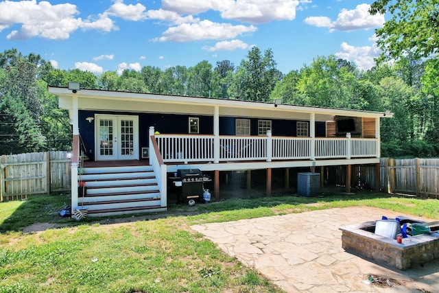 rear view of property featuring a yard, central AC, french doors, and a fenced backyard