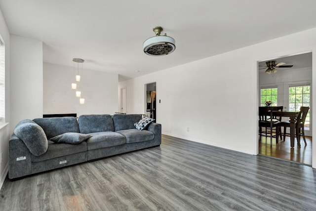 living area with baseboards, a ceiling fan, and wood finished floors