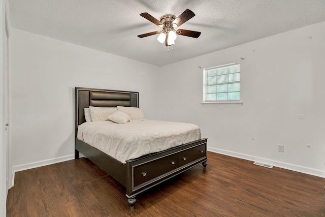 bedroom featuring a textured ceiling, baseboards, visible vents, and wood finished floors