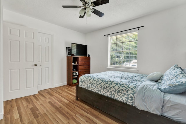 bedroom featuring a textured ceiling, a ceiling fan, baseboards, wood finished floors, and a closet