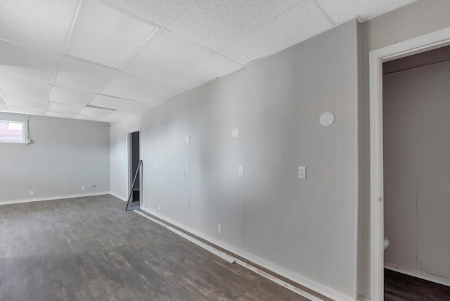 basement with a drop ceiling and dark wood-type flooring