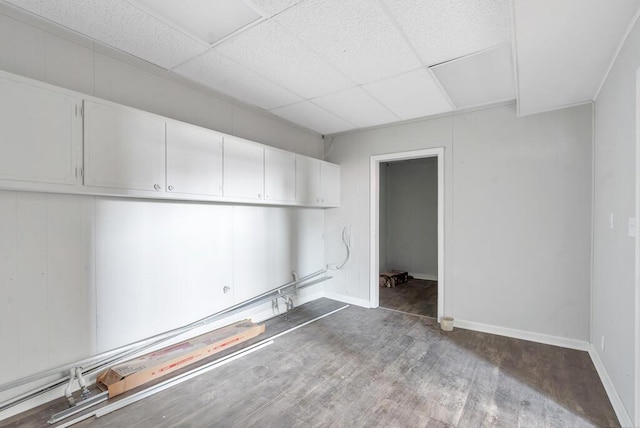 interior space with a drop ceiling and wood-type flooring