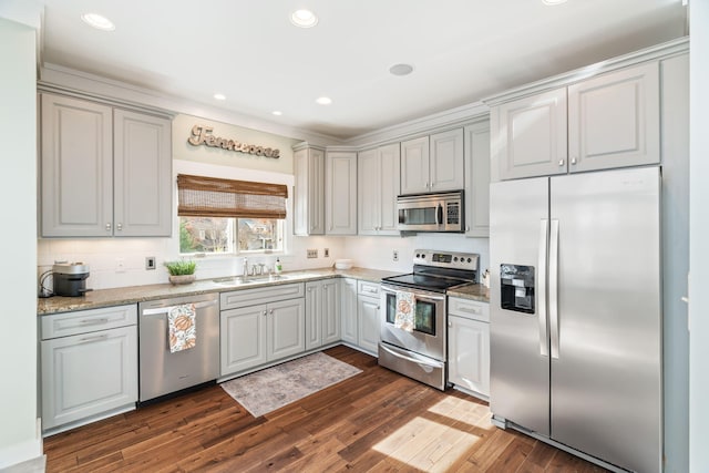 kitchen with gray cabinets, stainless steel appliances, dark hardwood / wood-style flooring, light stone counters, and sink