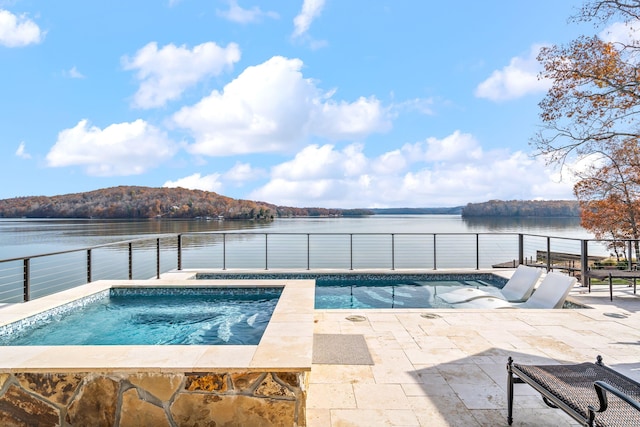 view of pool featuring a water view, a hot tub, and a patio