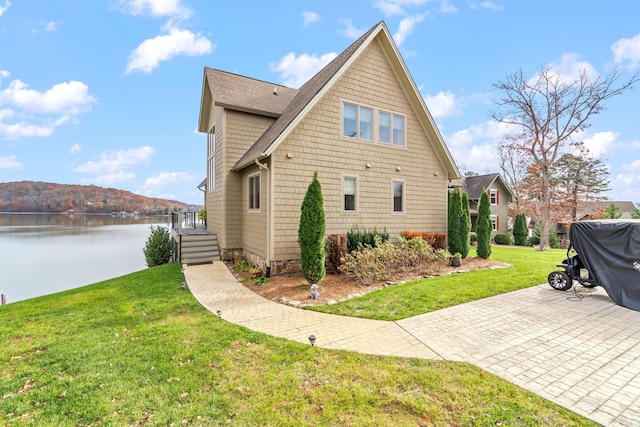 view of property exterior featuring a water and mountain view and a lawn