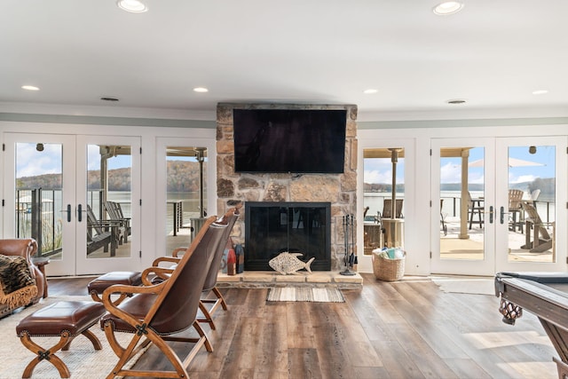 living room featuring french doors, a fireplace, crown molding, and wood-type flooring