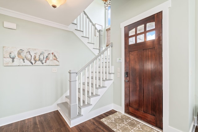 foyer with dark wood-type flooring and crown molding