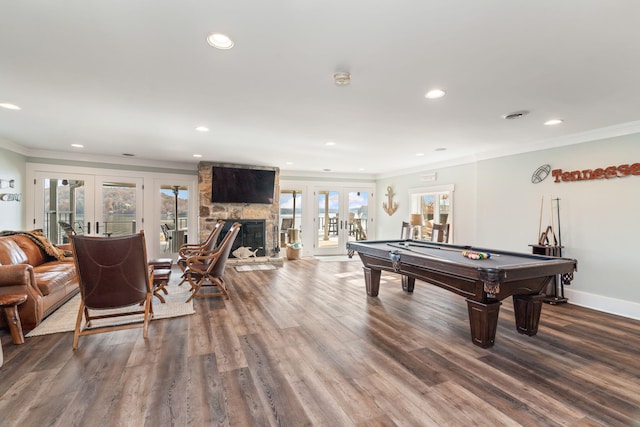 rec room featuring hardwood / wood-style flooring, a stone fireplace, ornamental molding, french doors, and pool table