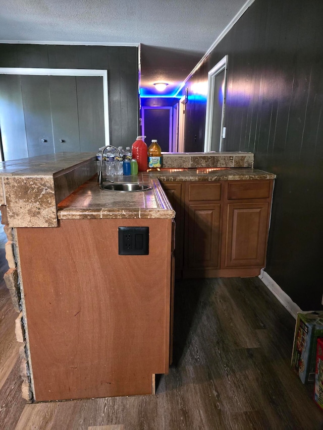 bar featuring a textured ceiling, dark hardwood / wood-style floors, sink, and wooden walls