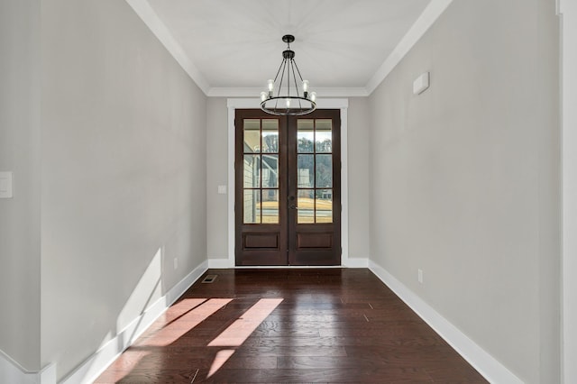 foyer featuring dark hardwood / wood-style flooring, french doors, ornamental molding, and an inviting chandelier