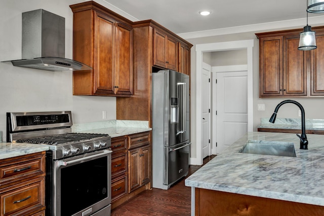 kitchen with light stone countertops, sink, wall chimney exhaust hood, decorative light fixtures, and high end appliances