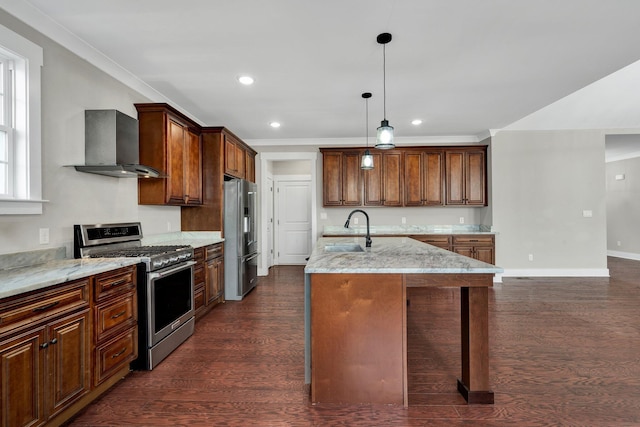 kitchen with a center island with sink, wall chimney range hood, hanging light fixtures, sink, and appliances with stainless steel finishes