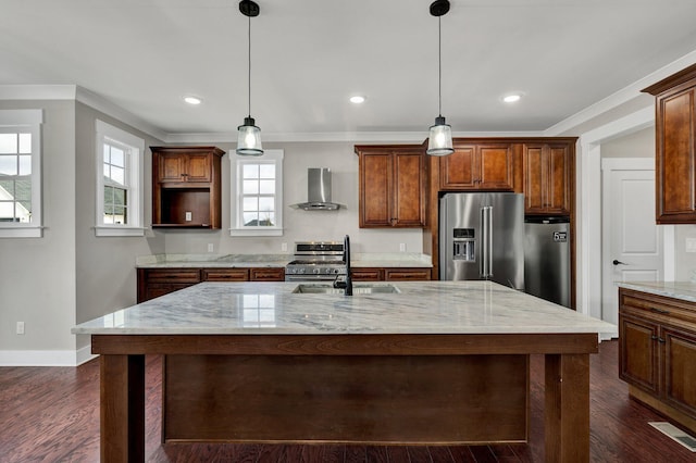 kitchen with wall chimney exhaust hood, light stone countertops, a kitchen island with sink, and appliances with stainless steel finishes