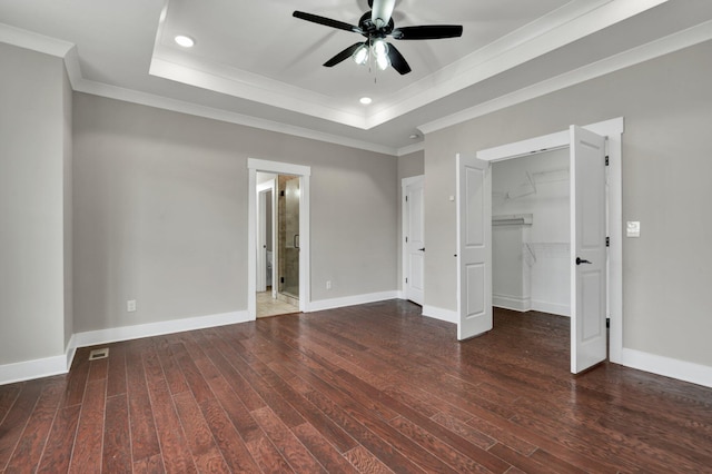 unfurnished bedroom with dark hardwood / wood-style flooring, ornamental molding, a tray ceiling, ceiling fan, and a closet