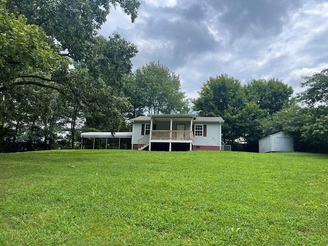 rear view of property with a storage unit, a porch, and a yard