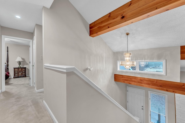 corridor featuring a healthy amount of sunlight, vaulted ceiling with beams, a chandelier, and light colored carpet