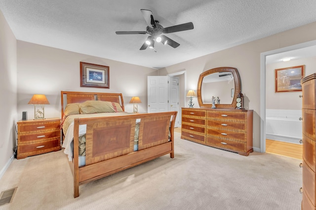 bedroom featuring connected bathroom, ceiling fan, light colored carpet, and a textured ceiling