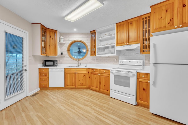 kitchen with sink, tasteful backsplash, light hardwood / wood-style flooring, a textured ceiling, and white appliances