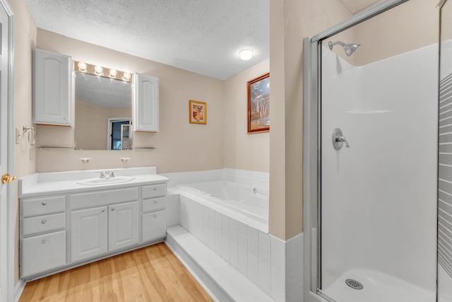 bathroom with vanity, separate shower and tub, wood-type flooring, and a textured ceiling