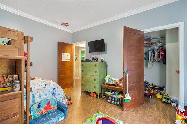 bedroom featuring ornamental molding, wood-type flooring, and a closet