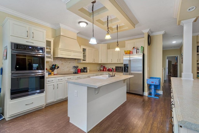 kitchen featuring appliances with stainless steel finishes, pendant lighting, sink, custom exhaust hood, and a kitchen island with sink