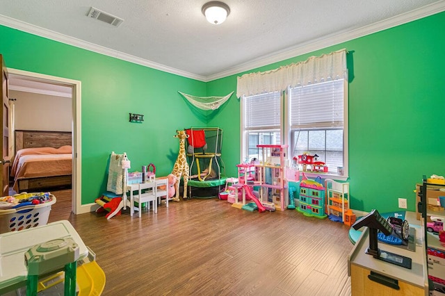 rec room with hardwood / wood-style flooring, ornamental molding, and a textured ceiling