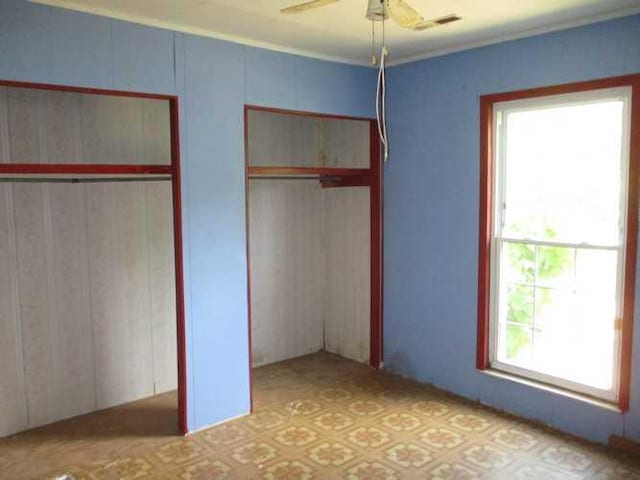 unfurnished bedroom with multiple windows and ceiling fan