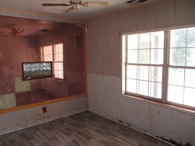 empty room featuring ceiling fan, dark hardwood / wood-style flooring, and wooden walls