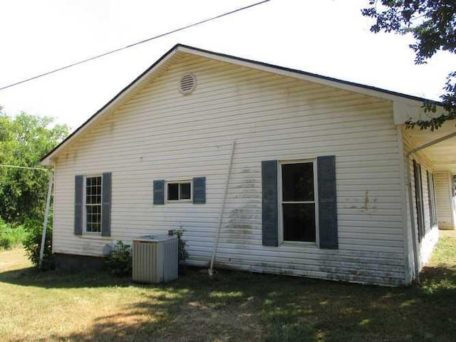 view of side of home with central air condition unit and a yard