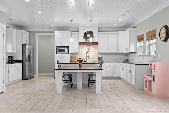 kitchen with a center island, pendant lighting, a breakfast bar, stainless steel appliances, and white cabinets