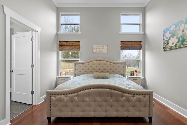 bedroom featuring dark hardwood / wood-style flooring, a high ceiling, and multiple windows