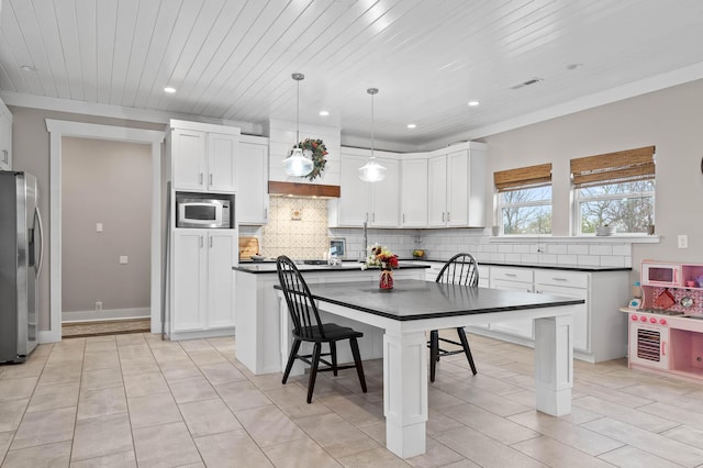 kitchen with appliances with stainless steel finishes, a kitchen bar, hanging light fixtures, and a center island