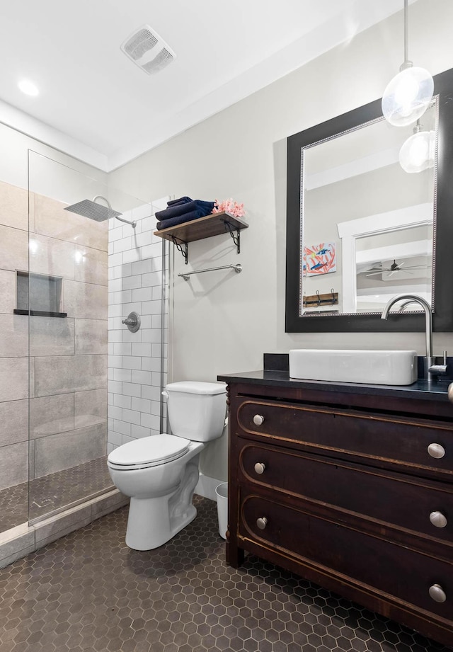 bathroom with toilet, vanity, tile patterned flooring, and a tile shower