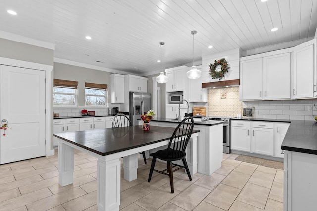 kitchen featuring decorative light fixtures, white cabinets, appliances with stainless steel finishes, and a kitchen island